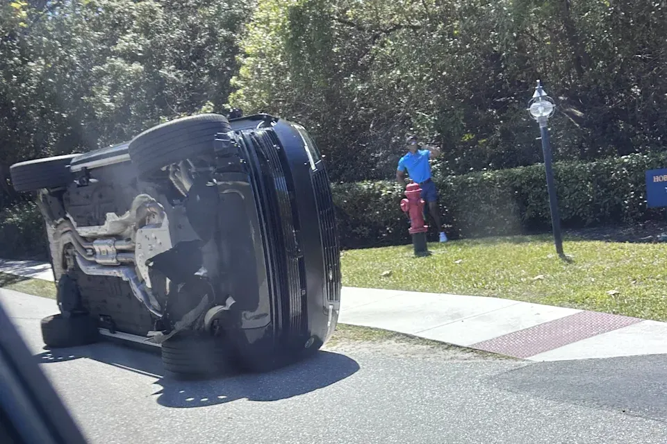 Tiger Woods stands near overturned vehicle after rollover crash in Jupiter Island Florida